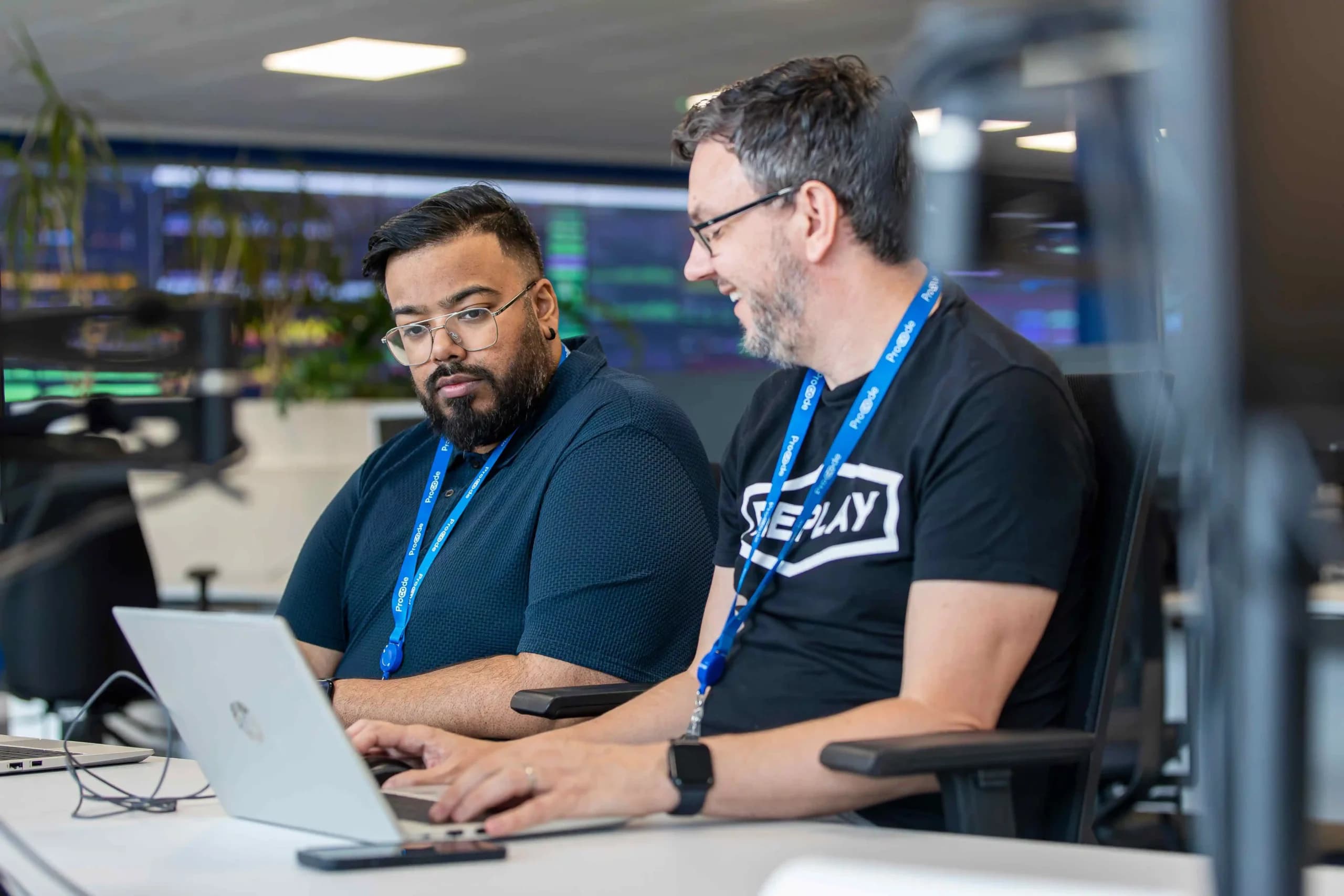 Two Procode engineers working on a shared laptop to improve smart metering solutions and data access for businesses.